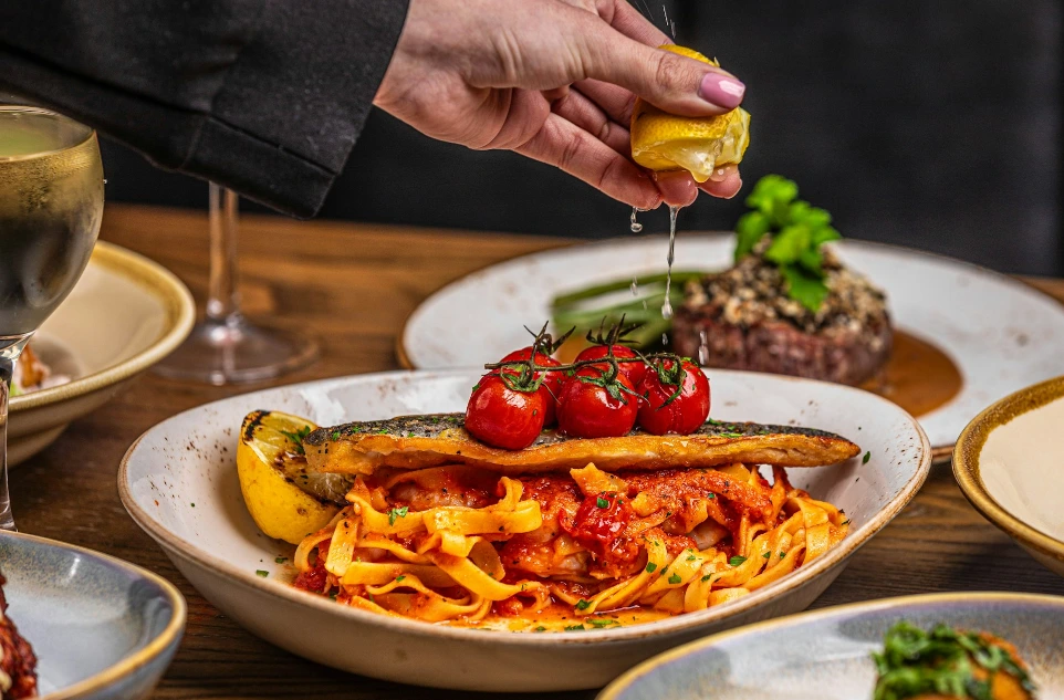 a person holding a slice of lemon over a plate of food